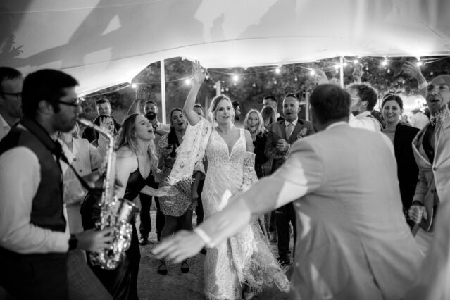 Getting the party started playing the saxophone with the bride, groom and guests dancing around.